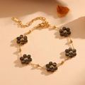 Detail of a golden chain bracelet featuring five dark floral beads with lobster clasp - Gold Black Cat's Eye Bracelet