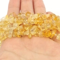 Macro detail of yellow natural agate crystal beads held in hand for DIY jewelry - Yellow Jade Chips