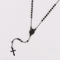 Detalle de un collar rosario negro con medalla de la Virgen María y colgante de cruz - Negro
