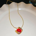 Dettaglio catena a serpente dorata con ciondolo in pietra rossa su piatto di ceramica bianca - Collana-Oro-Rosso