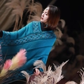 Close-up of bohemian knit poncho with teal diamond patterns and fringe trim detail - Twill Peacock Blue
