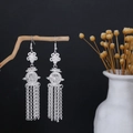 Detail of silver long tassel earrings with hollow lantern design on a wooden branch - Lantern Ball Tassel Style E6102-4