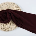 Deep red chiffon hijab scarf with fine rolled hem displayed on a natural woven mat - 128