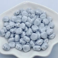 Macro view of light blue shell-shaped ceramic beads for jewelry making in a white dish - 12mm / Silver Grey