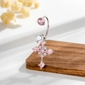 Zilveren navelpiercing met kruis en roze zirkonia op een houten ondergrond - Roze