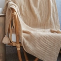 Nordic beige knitted waffle throw blanket with tassels draped on a chair - Khaki