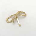 Close-up of golden bow hair clip with twisted rope texture in polished alloy metal - Gold