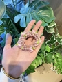 Pink pearl flower elastic hair scrunchie held against a natural green plant background - Champagne Pearl