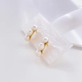 Macro shot of minimalist gold pearl earrings with three pearls in curved row on marble - Three Pearl Vertical Style