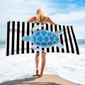 Microfiber beach towel with blue turtle on black and white stripes held by model - Blue Sea Turtle Black White Stripes (STJ-019-002)