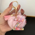 Detail of pink pompom keychain with resin letter Z featuring heart sequins and gold hardware - Letter Z