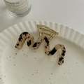 Detail of wavy tortoiseshell hair claw clip with gold metal spring on white ceramic tray - Light Leopard