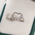 Gros plan d'une bague coeur argentée avec trois zircons dans un écrin à bijoux vert - Zirconia Blanc Plaqué Or Blanc