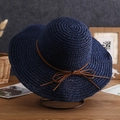 Close-up of navy straw sun hat with brown bow tie on a metal stand for women - One Size / Solid Color with Cord - Navy Blue