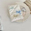 Detail of white quilted passport holder with blue and pink bows on a decorative plate - Creamy White Plaid