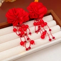 Detalle de pendientes de flores de tela roja con borlas de cuentas en un joyero beige - Pendientes de borla con cuentas de flores rojas (pin de plata)