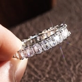 Macro shot of oval-cut zircon infinity ring in classic prong setting held by fingers - US 6 / Oval Cut