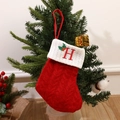 Red knit Christmas stocking with embroidered letter H hanging on a festive tree - Letter H