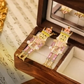 Orecchini schiaccianoci rosa con cristalli e perle sintetiche su una scatola di legno - Tema Rosa