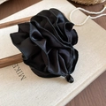Détail d'une pince à cheveux fleurie en satin plissé noir avec une perle centrale lisse - Noir