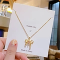 Halskette aus Titanstahl mit rosa Edelstein-Schleife und weißen Diamanten auf Display-Karte - Goldene rosa Diamantschleife
