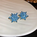 Close-up of blue gemstone flower earrings on a white tray with luxury gold plating - Gold Blue Faceted Gem Flower Studs (5#)