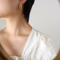 Elegant four-layer C-shaped gold earrings with zircon stones worn by a model - Gold