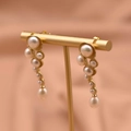 Golden drop earrings featuring cascading natural purple pearls and aquamarine accents - Natural Pearl Style
