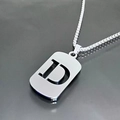 Macro de un collar de acero de titanio plateado con un colgante de chapa y la letra D - Letra D