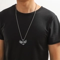 Gros plan d'un pendentif aile d'ange en acier inoxydable argenté sur un t-shirt noir - Aile d'ange