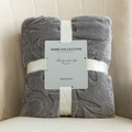 Grey flannel jacquard fleece blanket folded with gift ribbon on a beige sofa - Dark Gray