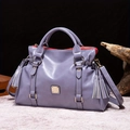 Detalle de bolso de cuero púrpura con borla decorativa y herrajes metálicos dorados - Azul Violeta