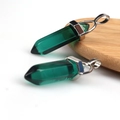 Detailed macro shot of two green hexagonal crystal pendants with secure metal clasps - Transparent Dark Green