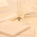 Golden maple leaf necklace with green orange gradient pendant on stone background - Green