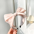 Detail of pink satin bow headband featuring a smooth texture and elegant oversized design - Pink