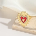 Macro shot of gold heart ring with red center and crystal wings on beige stone - Red Heart Sun Rays Style (JZ0603-1)