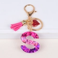 Detail of pink resin letter S keychain with glitter, leather tassel and heart charm - S