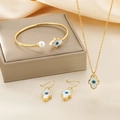 Hamsa Hand gold jewelry set with white shell and blue eye on beige silk backdrop - Hamsa Gold 3-Piece Set (KS192834-GC)