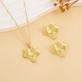 Dettaglio macro di un set di gioielli con ciondolo e orecchini a forma di foglia dorata - Stile Foglia D'oro