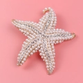 Detalle de broche estrella de mar con perlas blancas y cristales sobre base metálica - Estrella de Mar Dorada