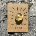 Yellow crystal gemstone on brown gift card with You're a Real Gem text on rock texture - Citrine