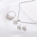 Silbernes geometrisches Schmuckset mit glitzernden Strasssteinen auf weißem Seidenhintergrund - Halskette+Ring+Ohrstecker / Silber
