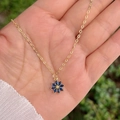 Collier élégant à pendentif fleur dorée serti de zircons bleus porté à la main - Bleu