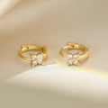 Macro shot of gold floral earrings with clear zircon stones on soft silk fabric - Gold Flower Zirconia Earring