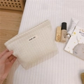 Detalle de bolsa de cosméticos tejida en color beige con etiqueta Simple Wish sostenida - Pequeño / Blanco Roto