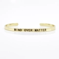 Gold-plated 4mm stainless steel cuff bracelet engraved with MIND OVER MATTER text - MIND OVER MATTER