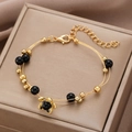 Gold beaded bracelet featuring black floral charm and spheres on a soft beige background - Gold Wire Woven Black Bead Flower Bracelet (9416)