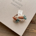 Detail of two beige fabric bunny hair ties with carrot accents on a rustic background - Carrot Rabbit Hair Tie