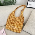 Détail d'un sac cabas en toile à carreaux jaunes avec broderie sur un canapé chic - Grille Orange Jaune