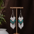 Detail of Bohemian silver feather earrings with blue beads on a metal display stand - Blue Silver (E1222-3)